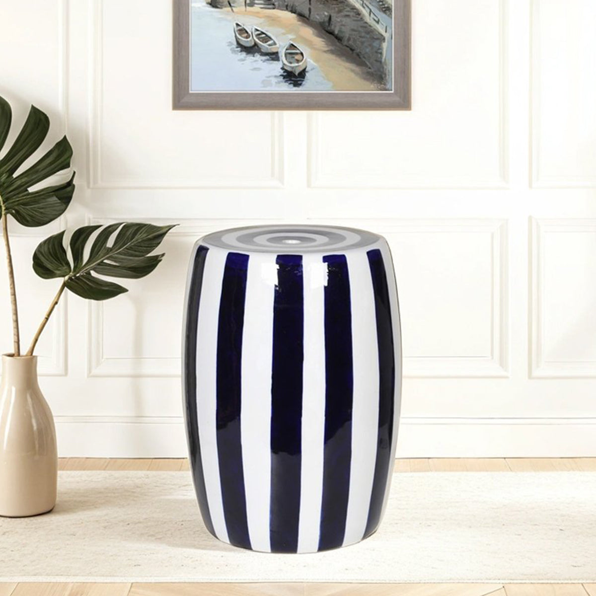 Navy and white striped stool in a room with a framed picture and plant.