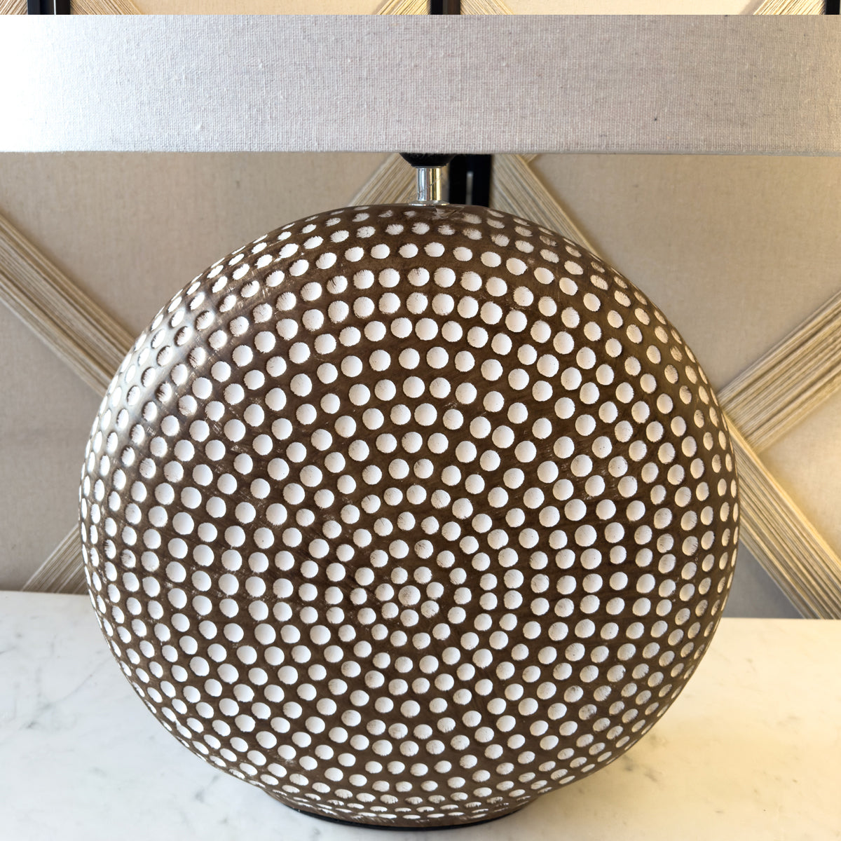 A circular brown lamp base with an off white linen shade.