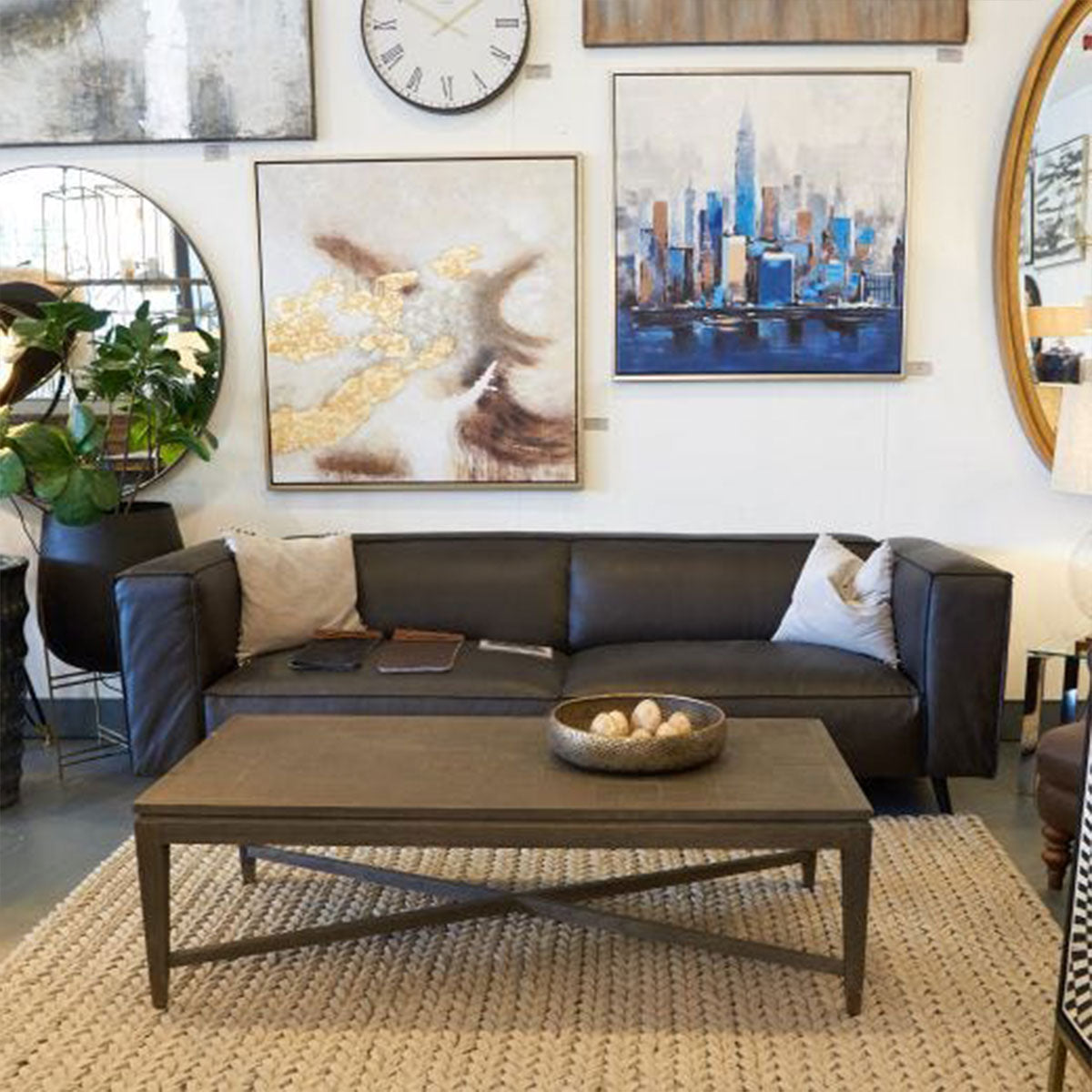 Modern living room with a black sectional sofa, coffee table, and decorative wall art.