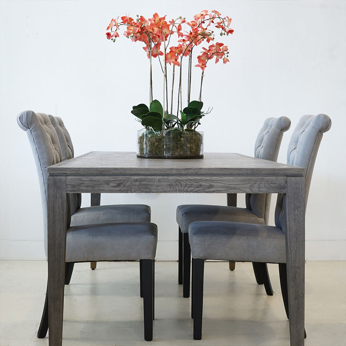 Grey wooden parquet dining table with 4 chairs and an orchid