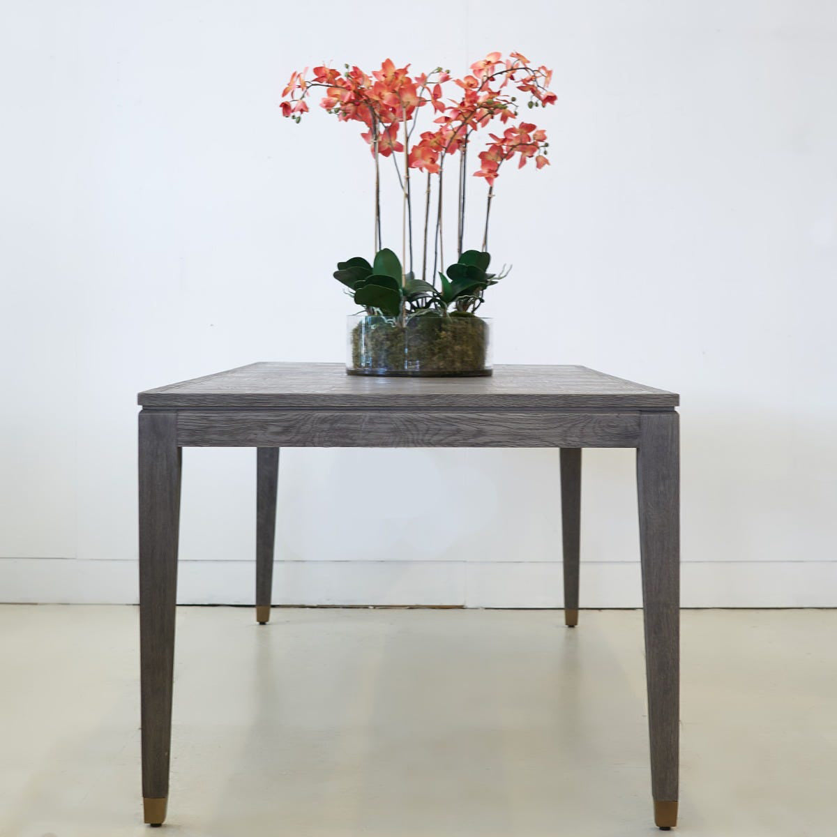 Grey oak dining table with a pink ochid on top