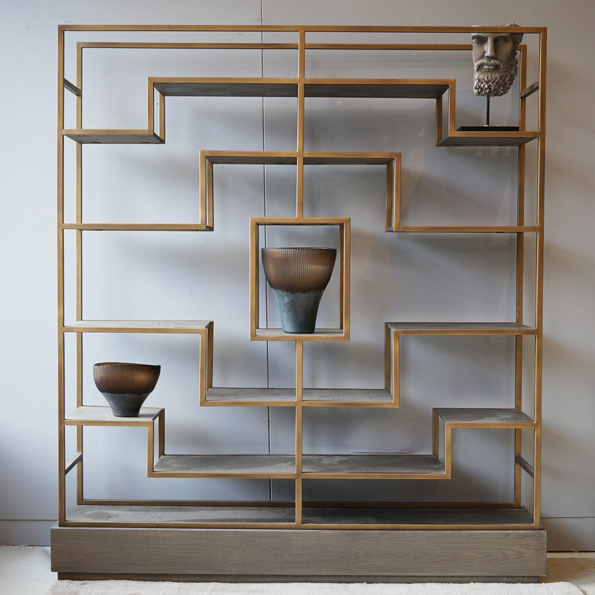 Decorative shelving unit with geometric design and parquet surfaces.