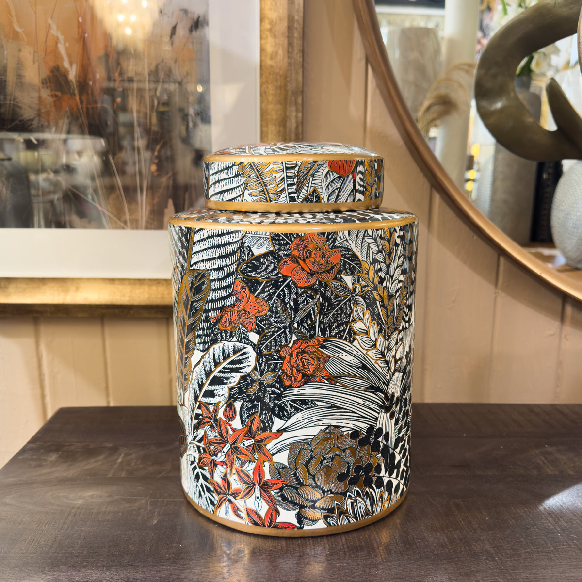 Decorative ceramic jar with floral and leaf patterns on a wooden surface.