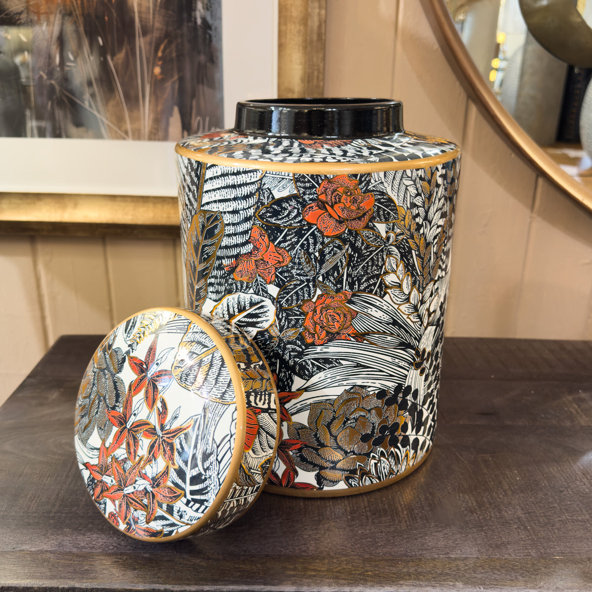Decorative cylindrical ginger jar with floral pattern on a wooden surface