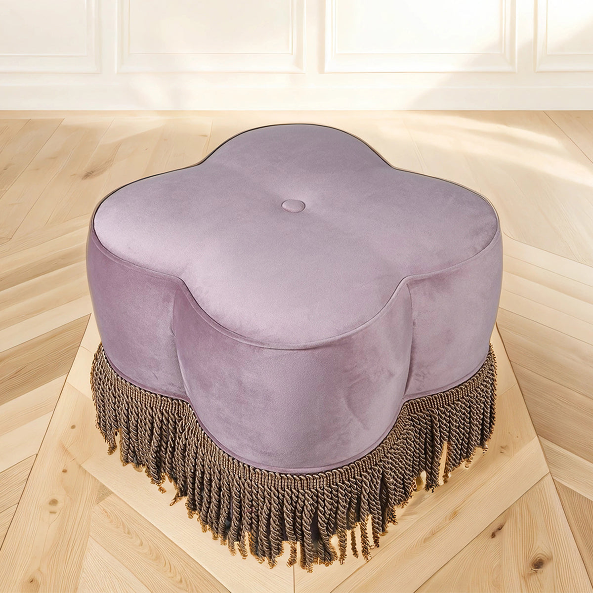 Purple ottoman with fringe on a wooden floor