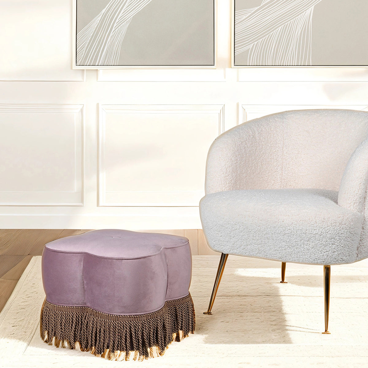 Purple ottoman with fringe and white chair in a room with abstract wall art.
