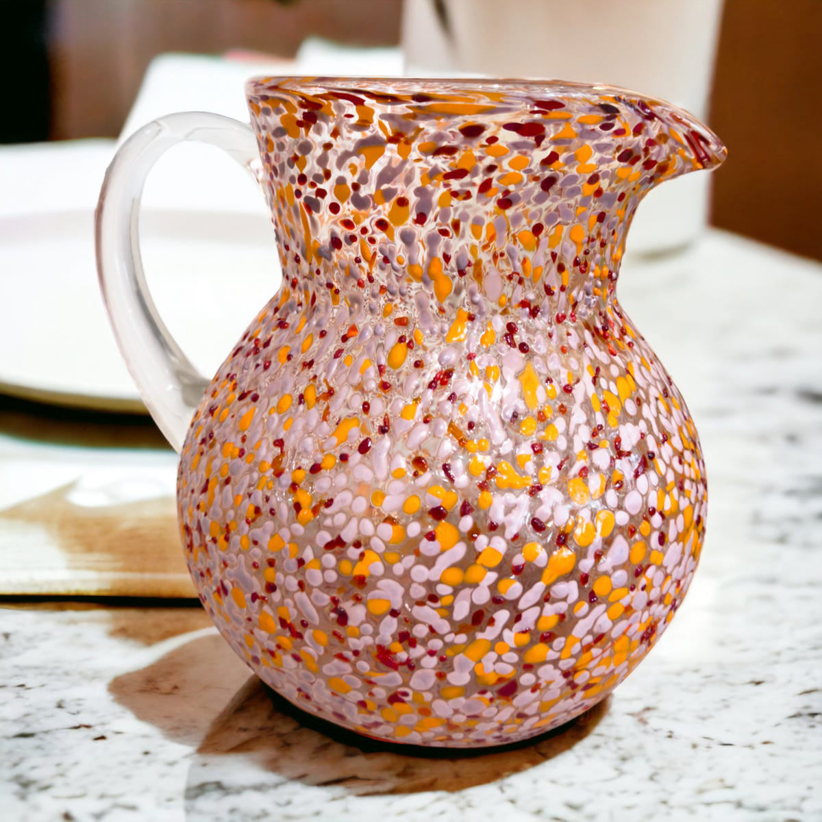 Decorative glass pitcher with speckled pattern on a marble surface
