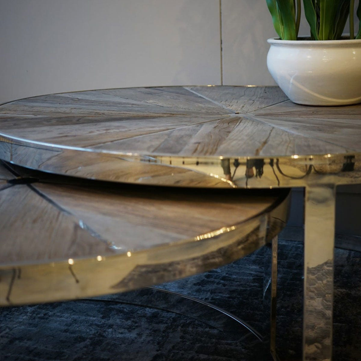 Round wooden table with a potted plant in the background