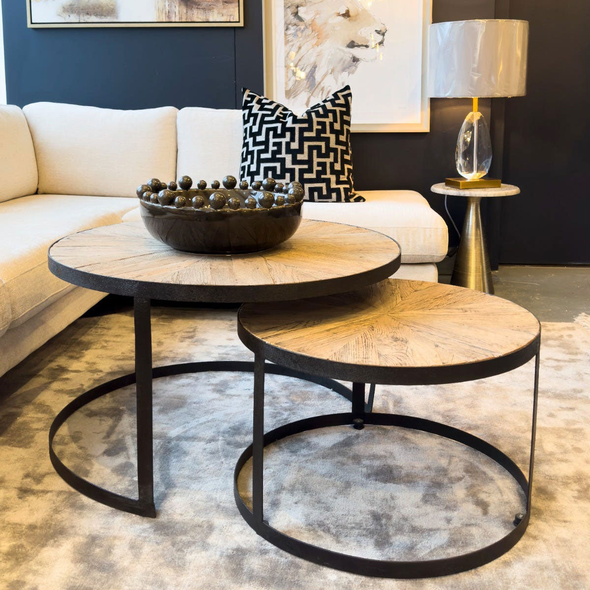 Two round reclaimed wood coffee tables with metal legs in a living room setting.