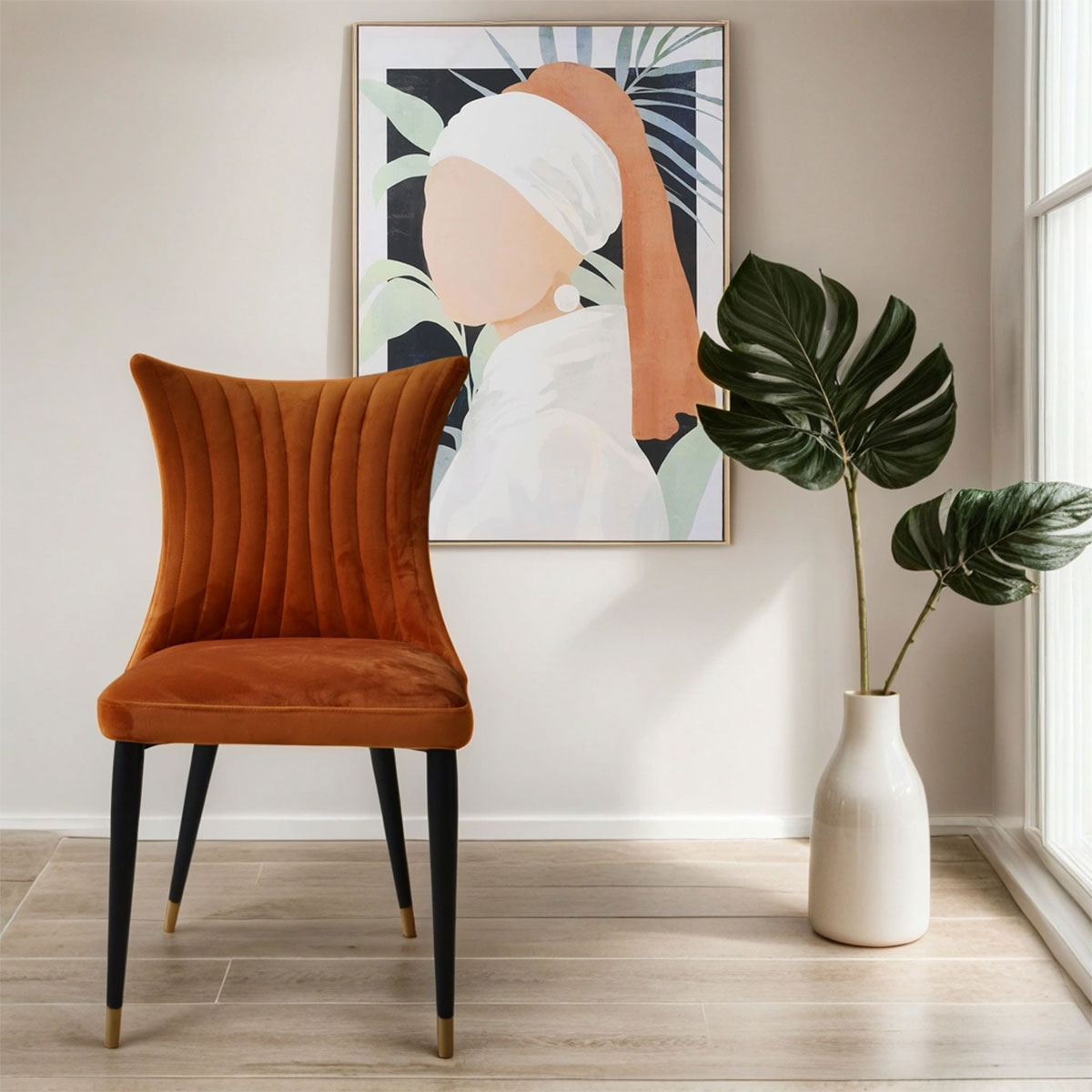 Rust orange velvet dining chair in a room with a painting and plant