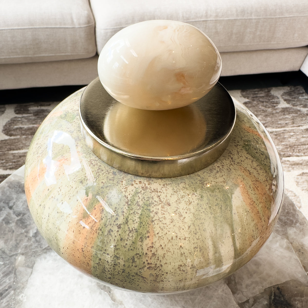 Decorative stone lidded jar with a spherical top on a marble surface