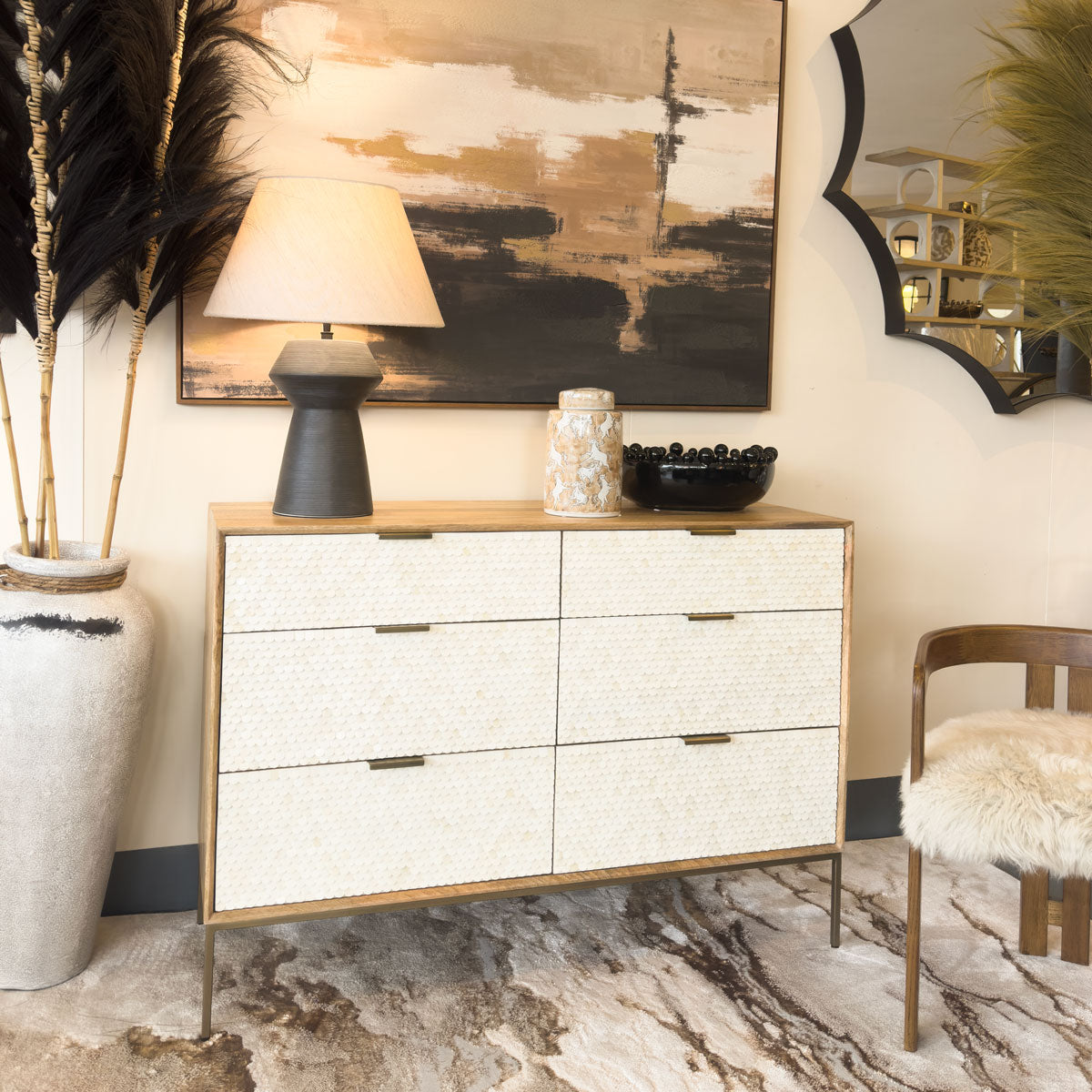 White dresser with gold accents in a stylish room with abstract art and decor.