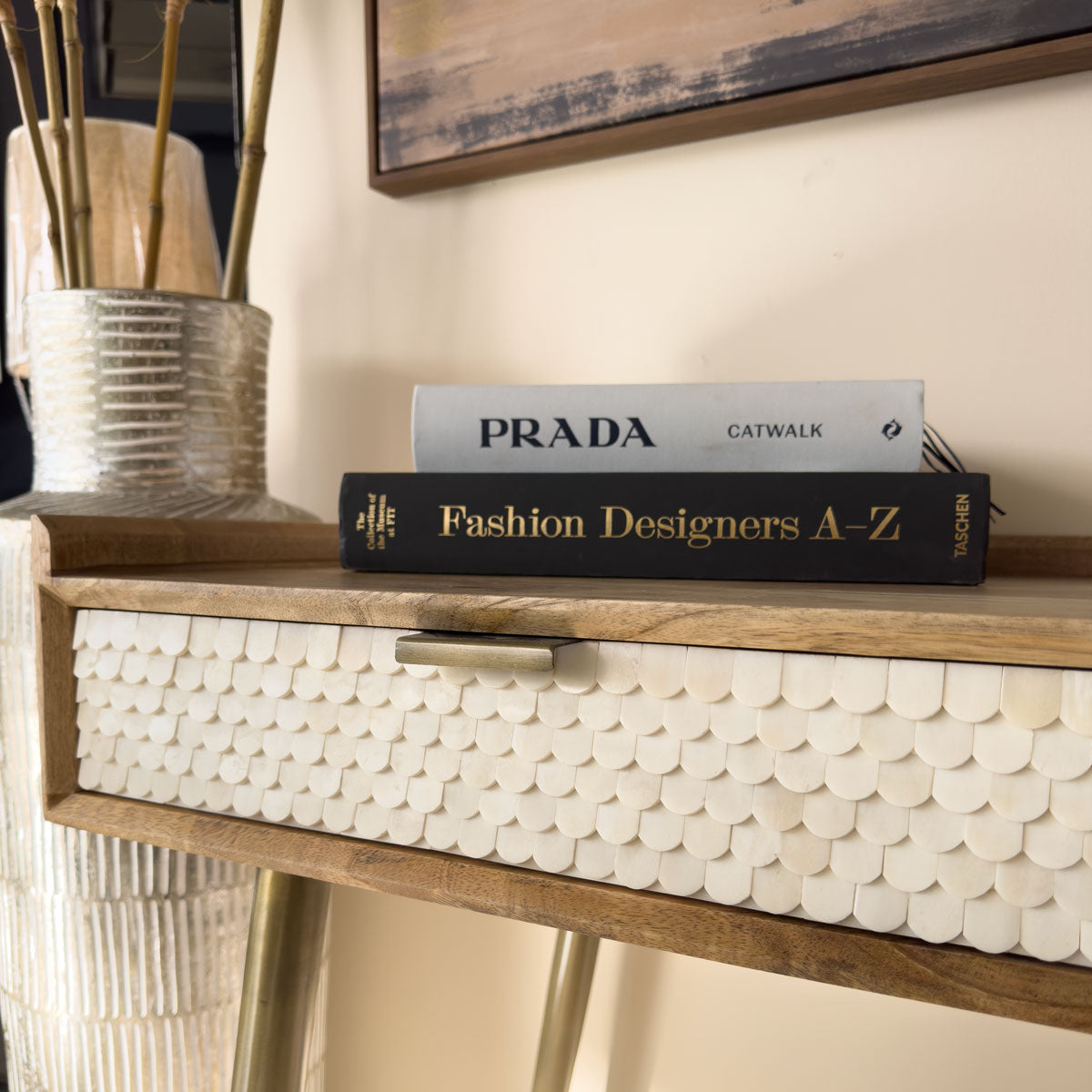 Two books on a bone console table surface with a decorative background
