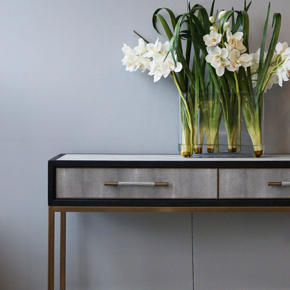 Black & white console table with a vase of white flowers against a gray wall