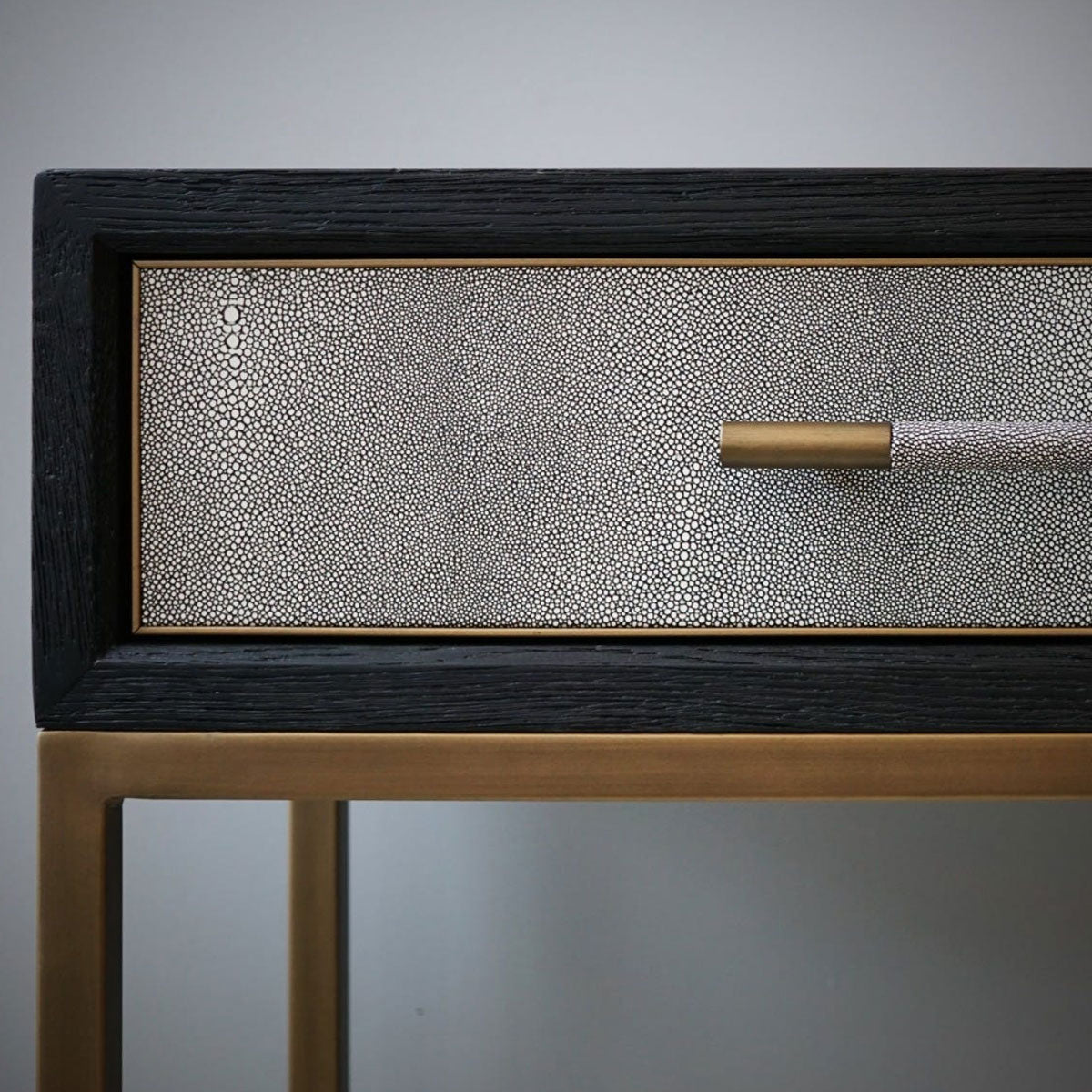 Shagreen console table with a textured drawer and gold handle against a gray background