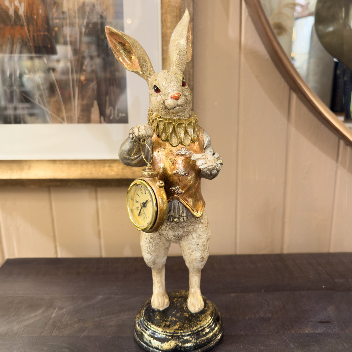 Decorative rabbit figure with gold attire and clock, placed on a surface.