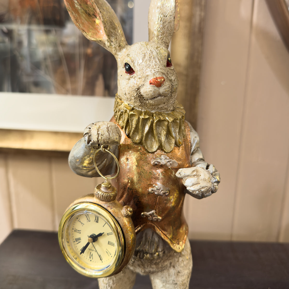 Decorative rabbit figure holding a clock against a neutral background