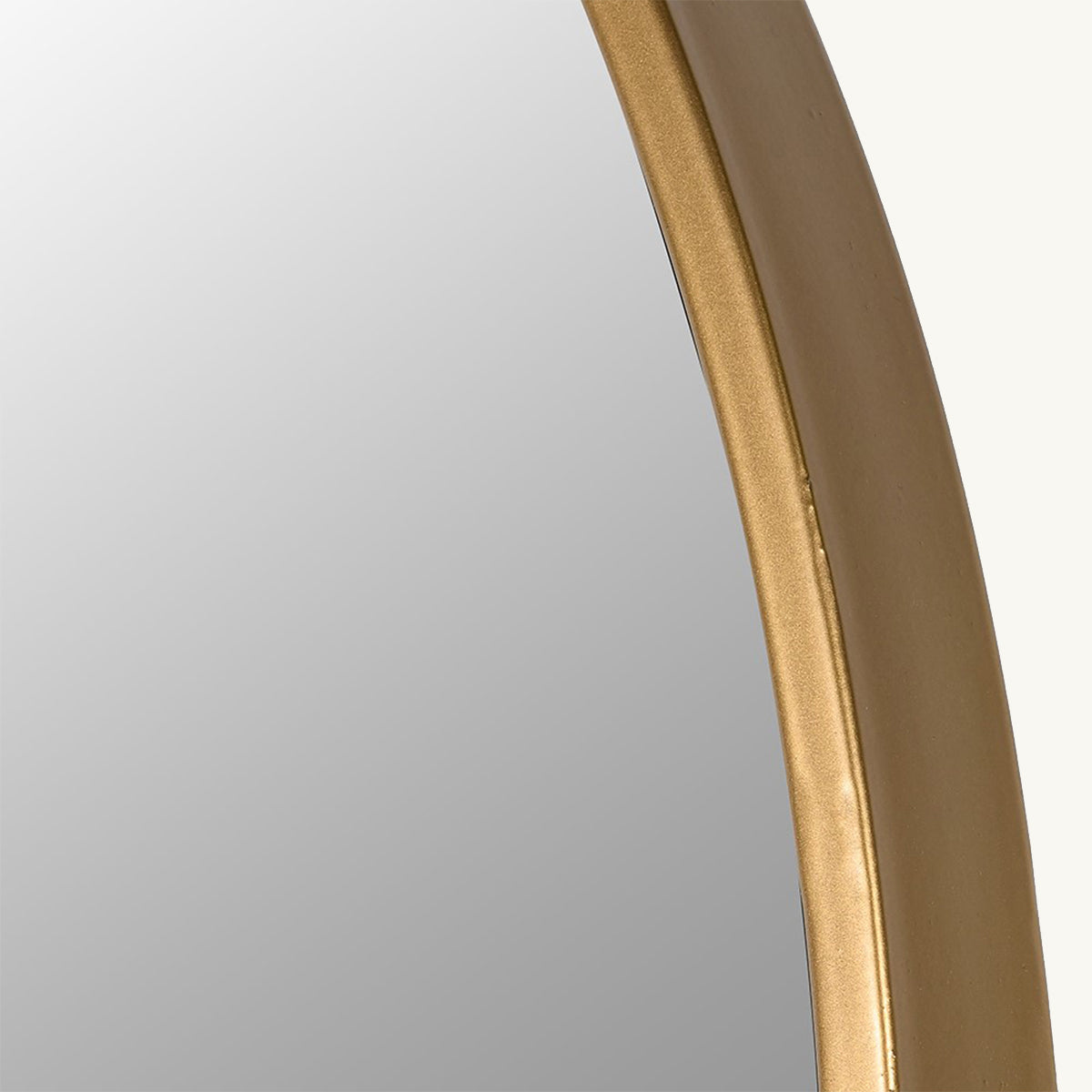 A close up of an arched wall mirror with a minimalistic gold frame.