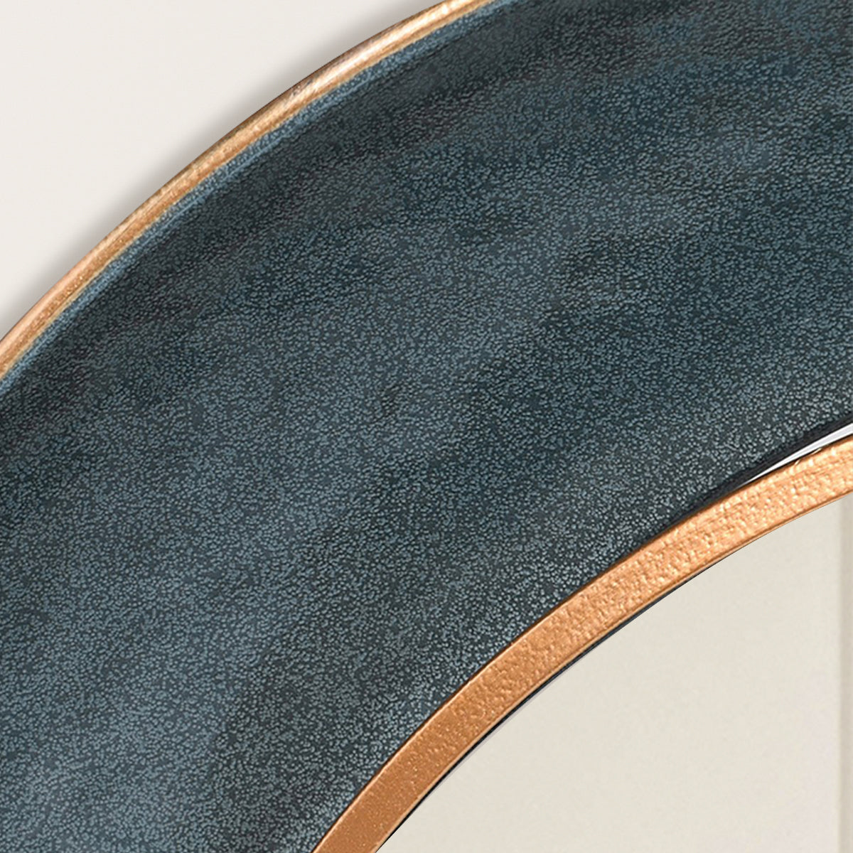 A close up of a teal and gold round wall mirror.