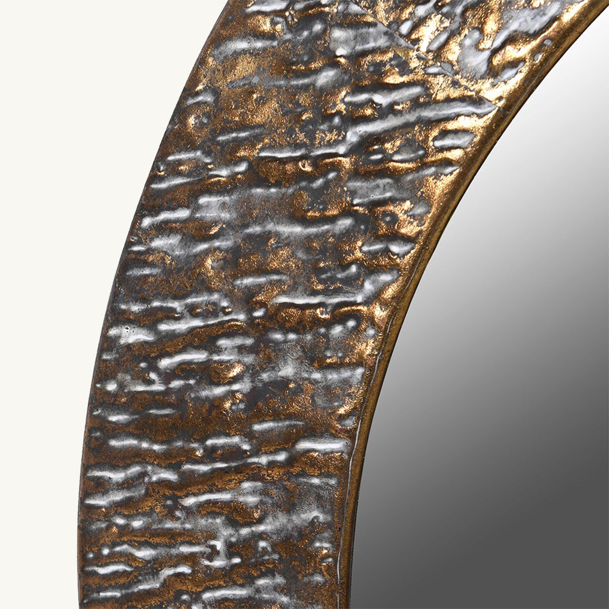 A close up of a hammered metal framed mirror in a golden tone.