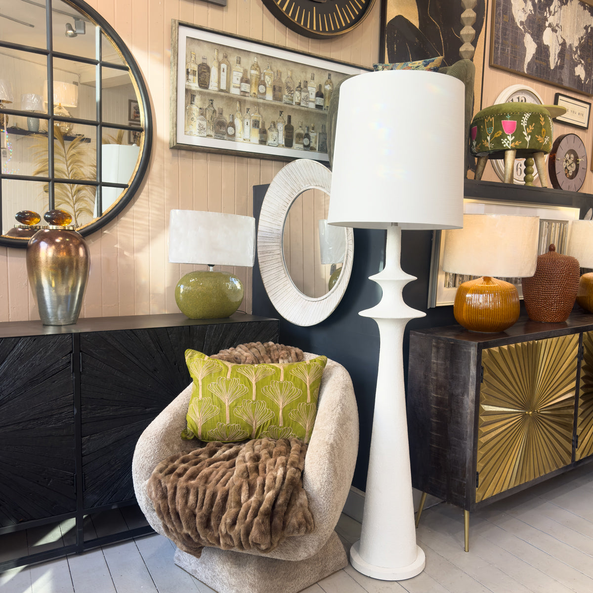 Decorative interior setting with a white lamp, round mirror, and furniture.