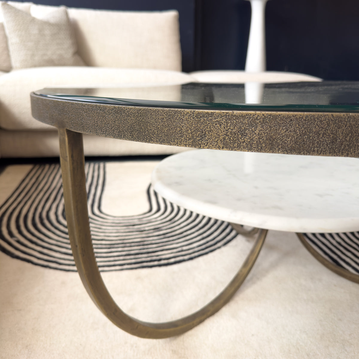 Glass coffee table with textured base on a carpeted floor