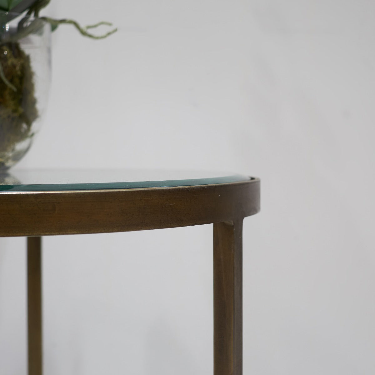 Small round table with a glass top and brass frame against a plain background