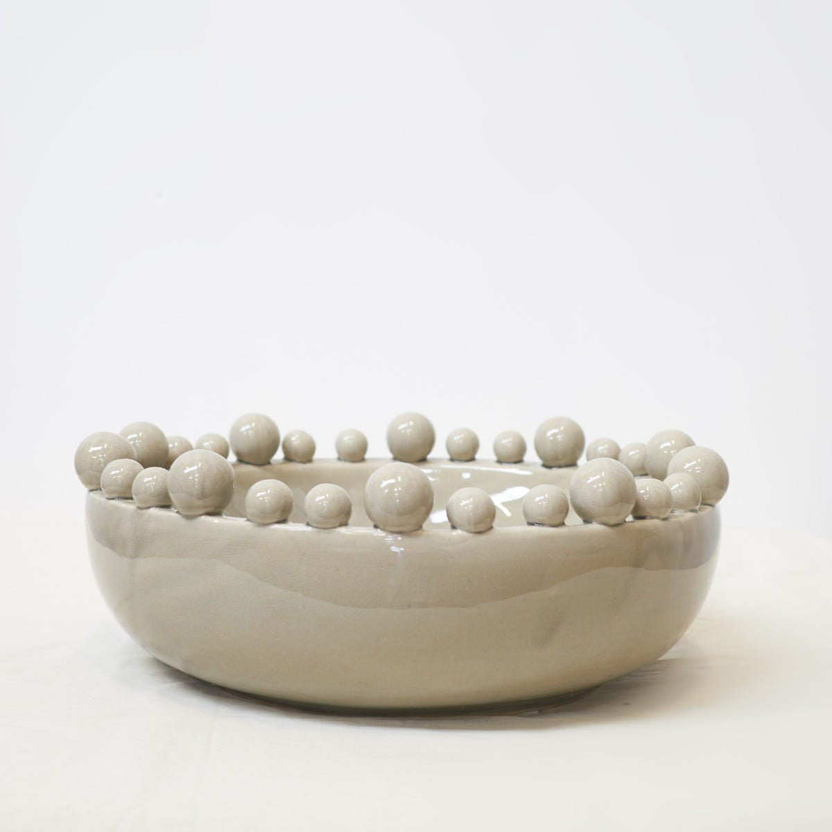 A grey glossy bobble bowl for home decoration, sitting against a white background.
