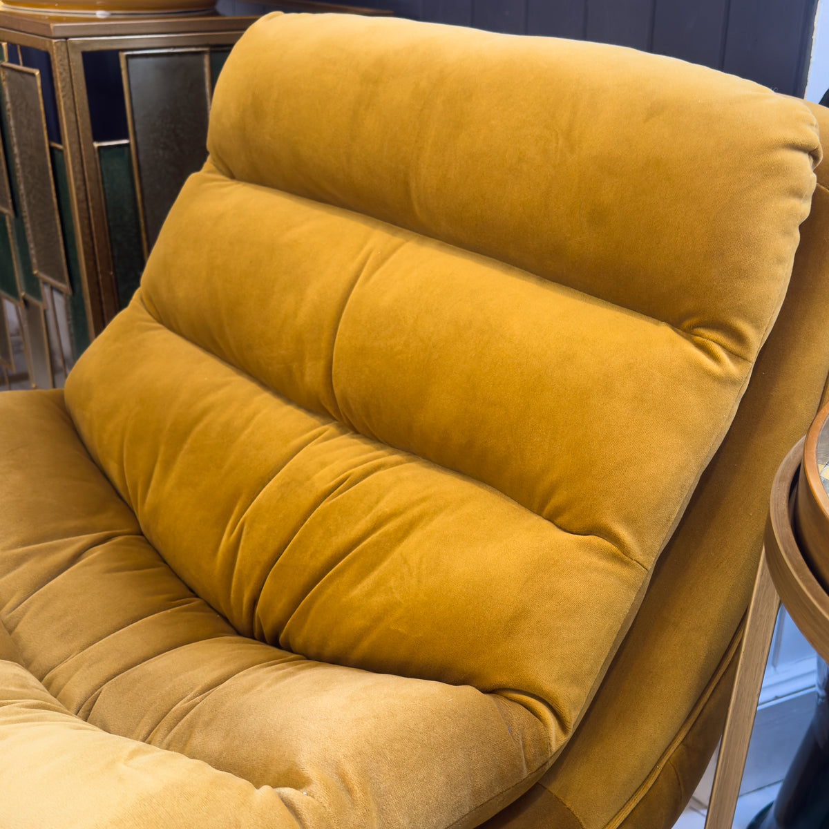 A close up of a mustard coloured padded lounge chair.
