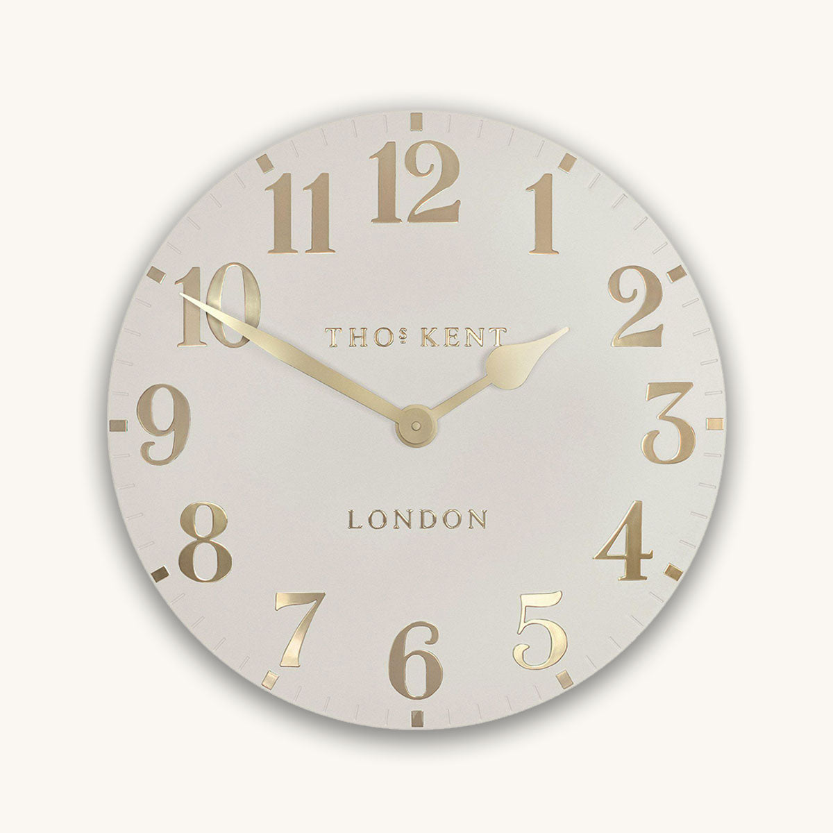 Cream round clock with gold numbers and 'Thomas Kent London' branding on a white background