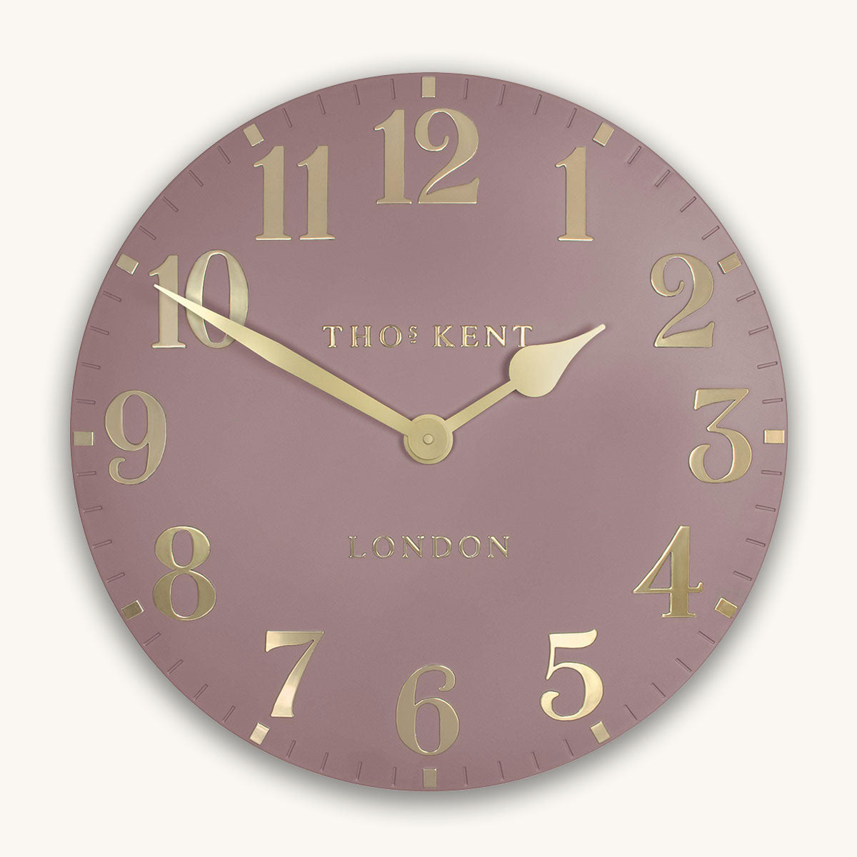 Wall clock with gold numbers and 'Thomas Kent London' branding on a light pink background