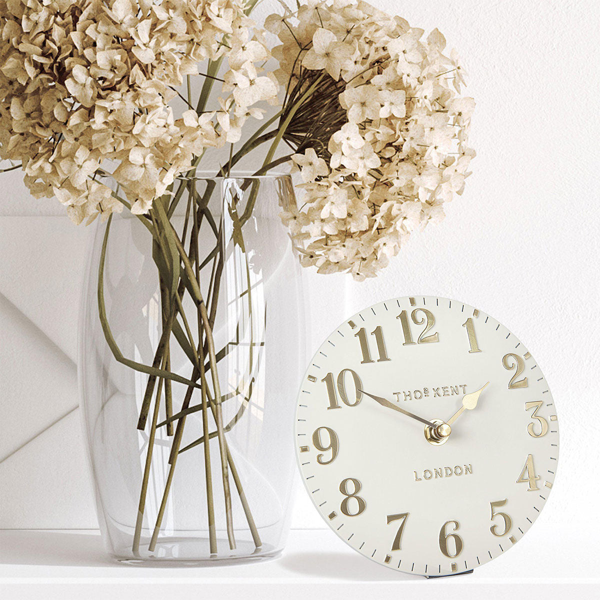 Decorative clock with a vase of flowers on a light background
