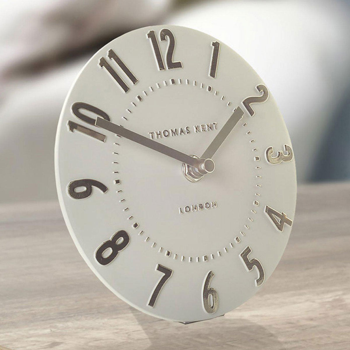 Silver clock with Roman numerals on a wooden surface