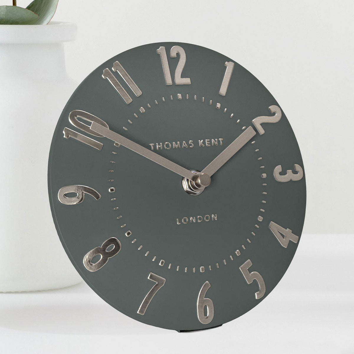 Green clock with silver accents on a white background, featuring the brand 'Thomas Kent'.