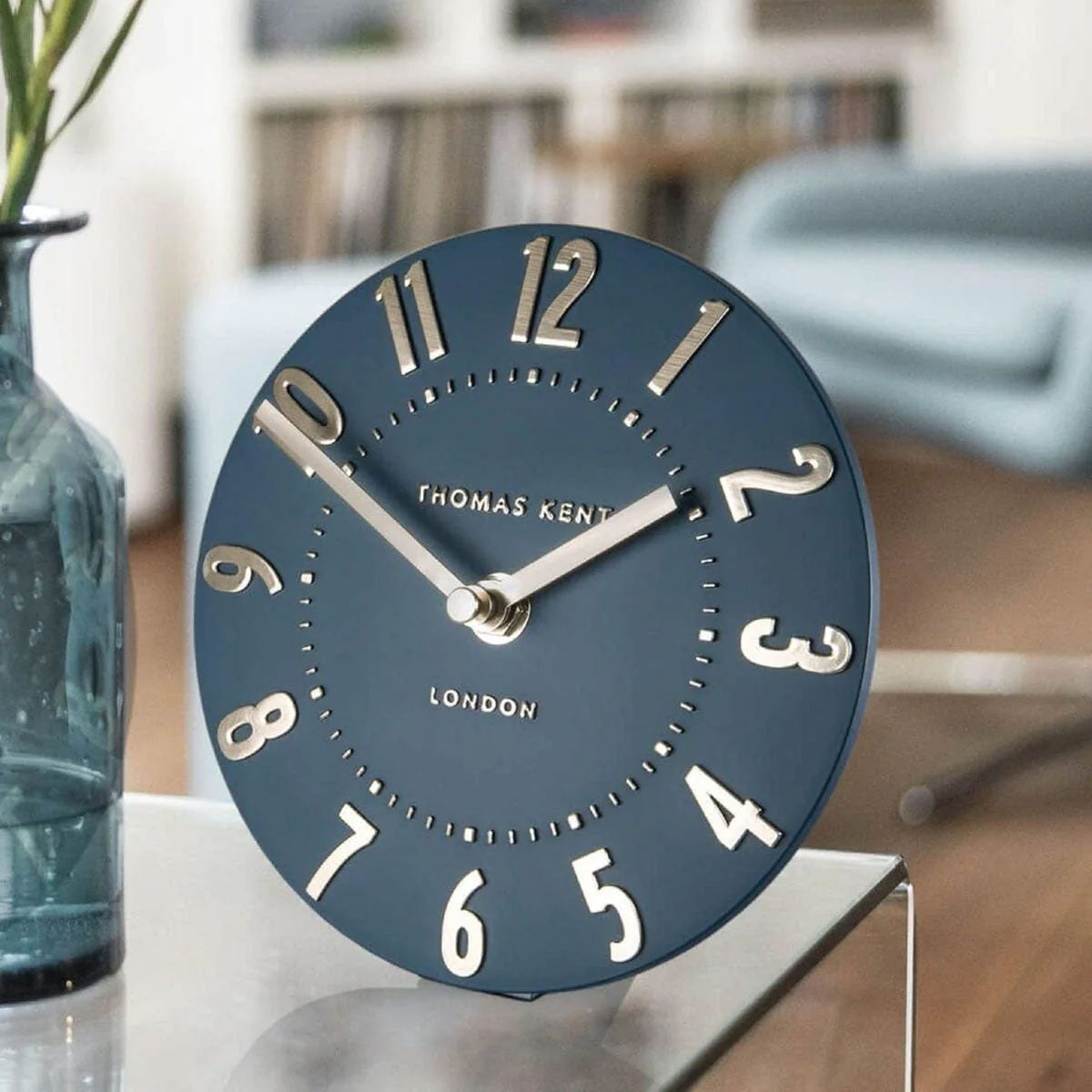 Blue clock with 'Thomas Kent London' branding on a table.