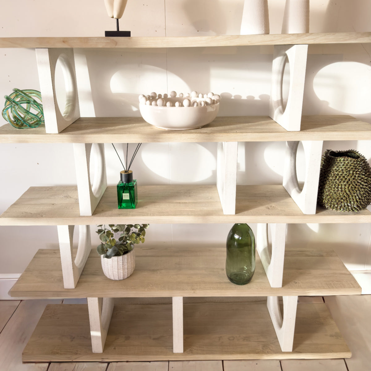 Wooden shelf with decorative items including a green vase and a plant.