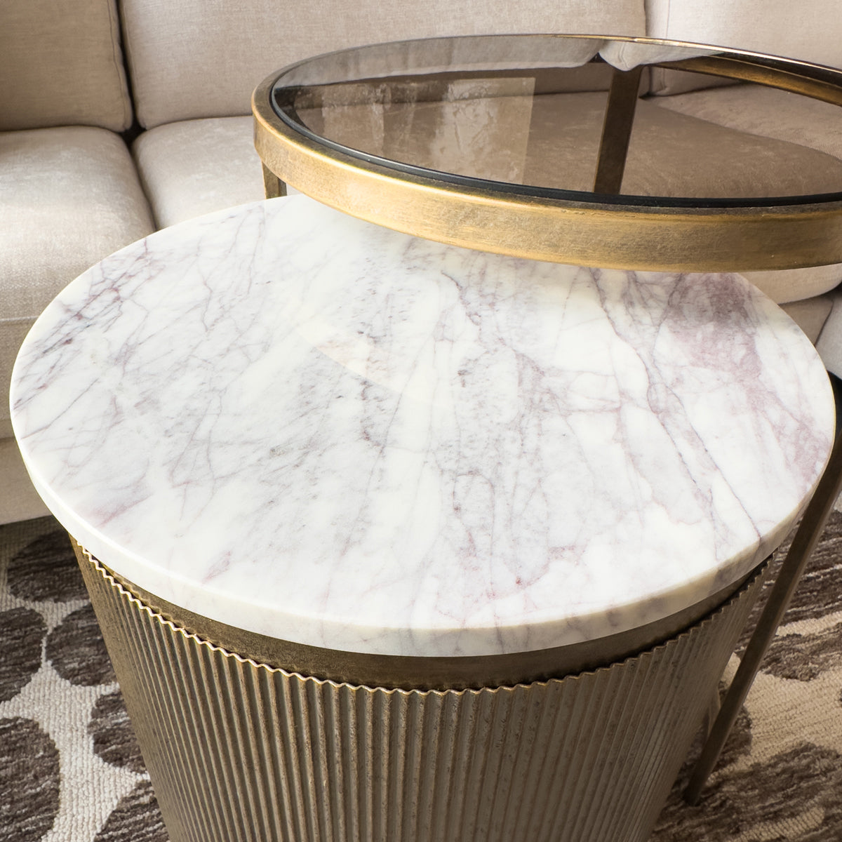Round marble side table with gold base in a living room setting