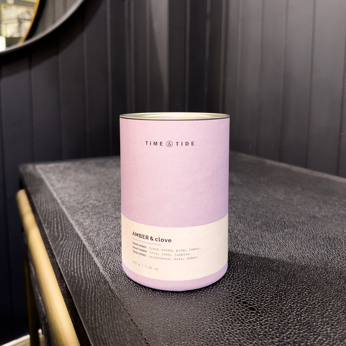 Cylindrical product packaging with 'Time & Tide' branding on a dark surface.