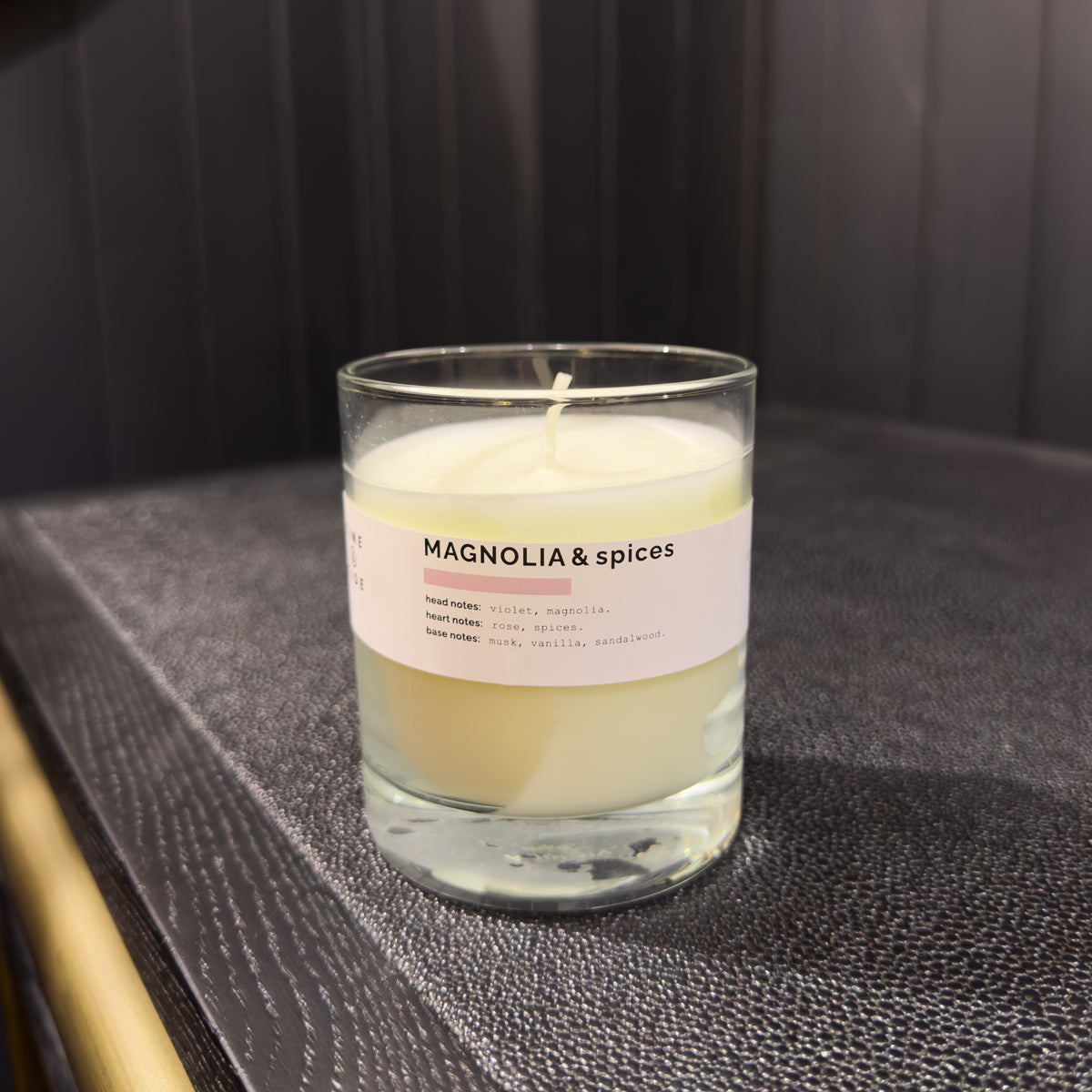 Candle in a glass jar with a label on a textured surface