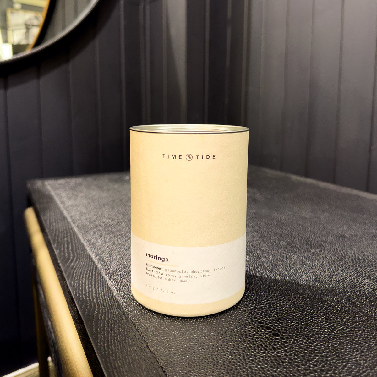 Candle labeled 'Time & Tide' on a textured surface with a dark background