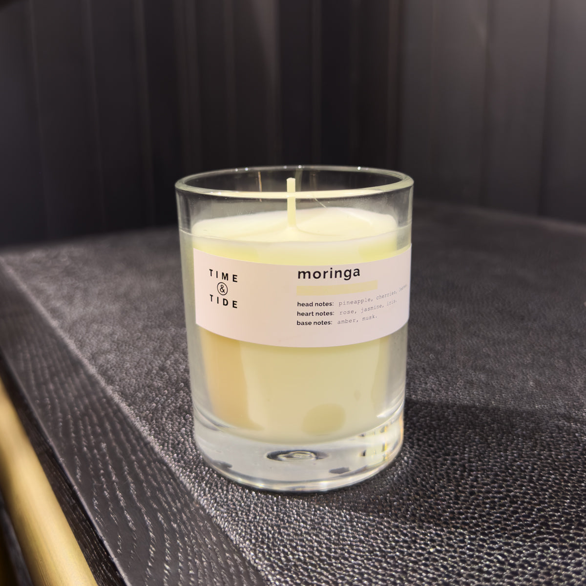 Candle in a glass jar with a label on a dark surface