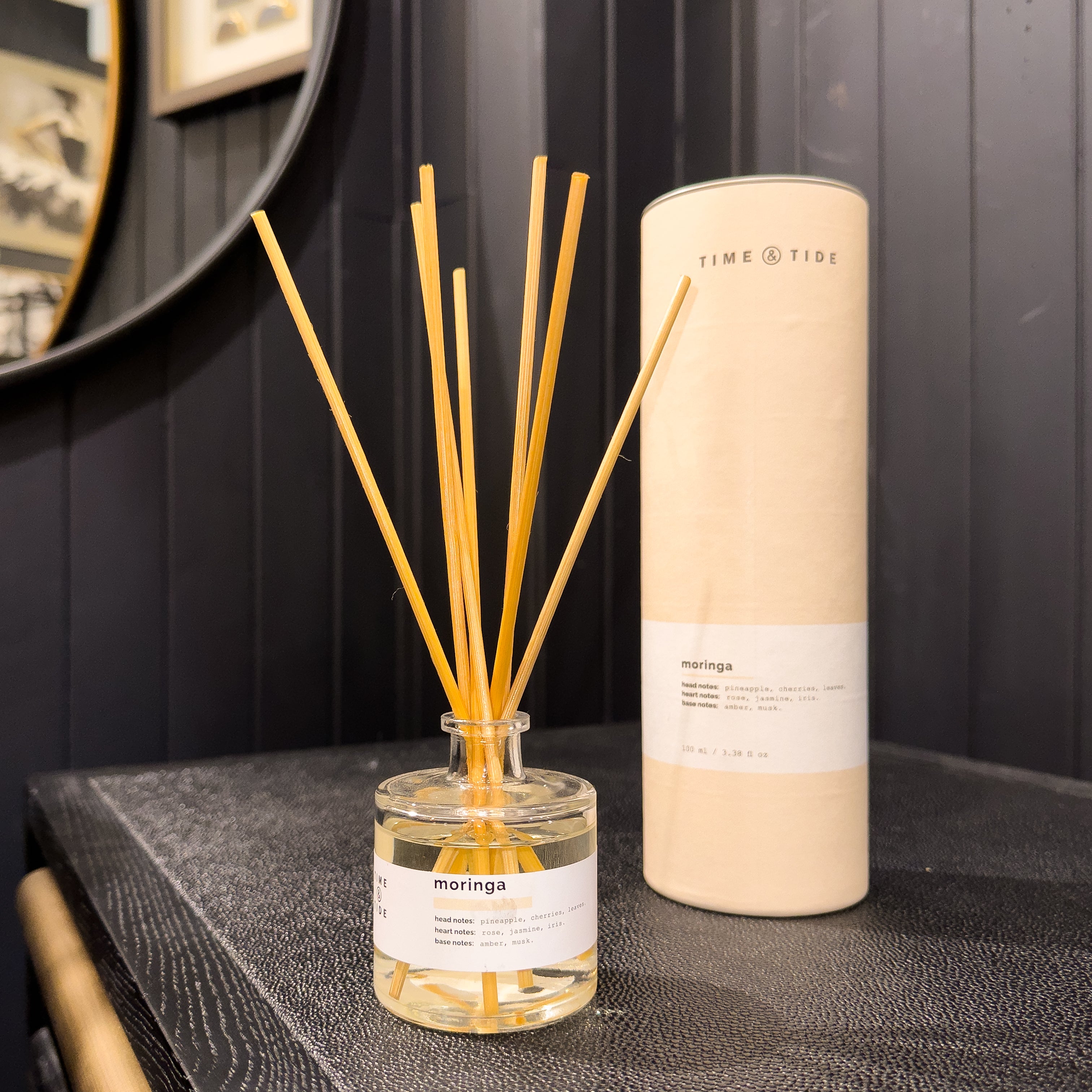 Reed diffuser with sticks and cylindrical container on a dark surface