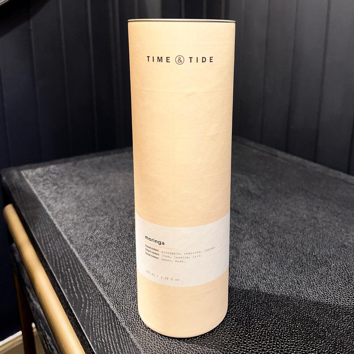 Cylindrical product packaging with 'Time & Tide' branding on a dark surface.