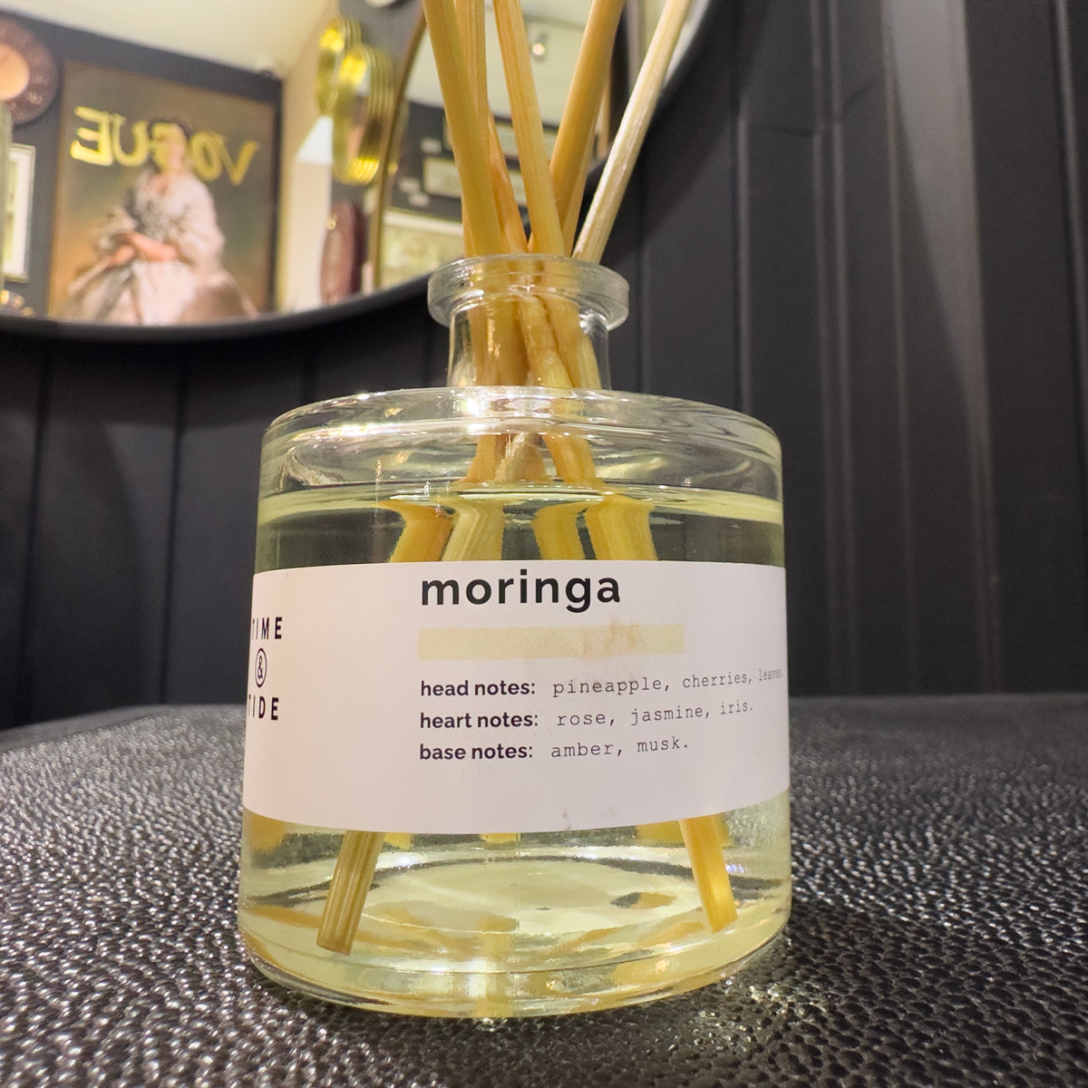 Clear diffuser bottle with yellow sticks and a label on a textured surface.