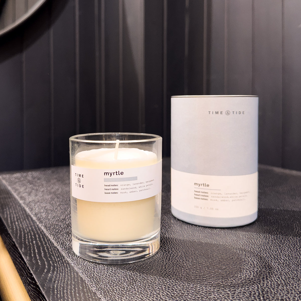 Candle and its packaging labeled 'myrtle' on a dark surface.