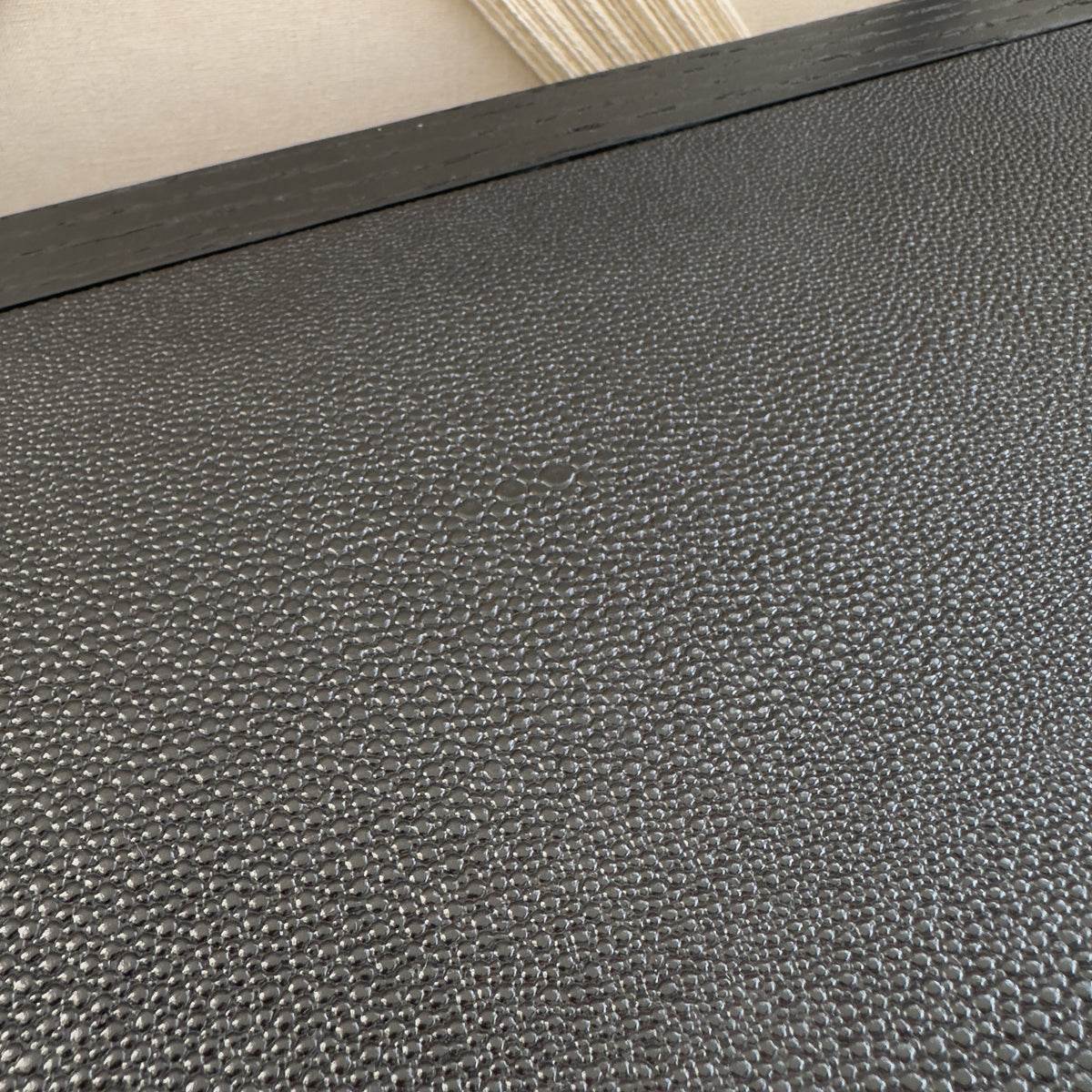 A close up of a console table top made from black faux shagreen material.
