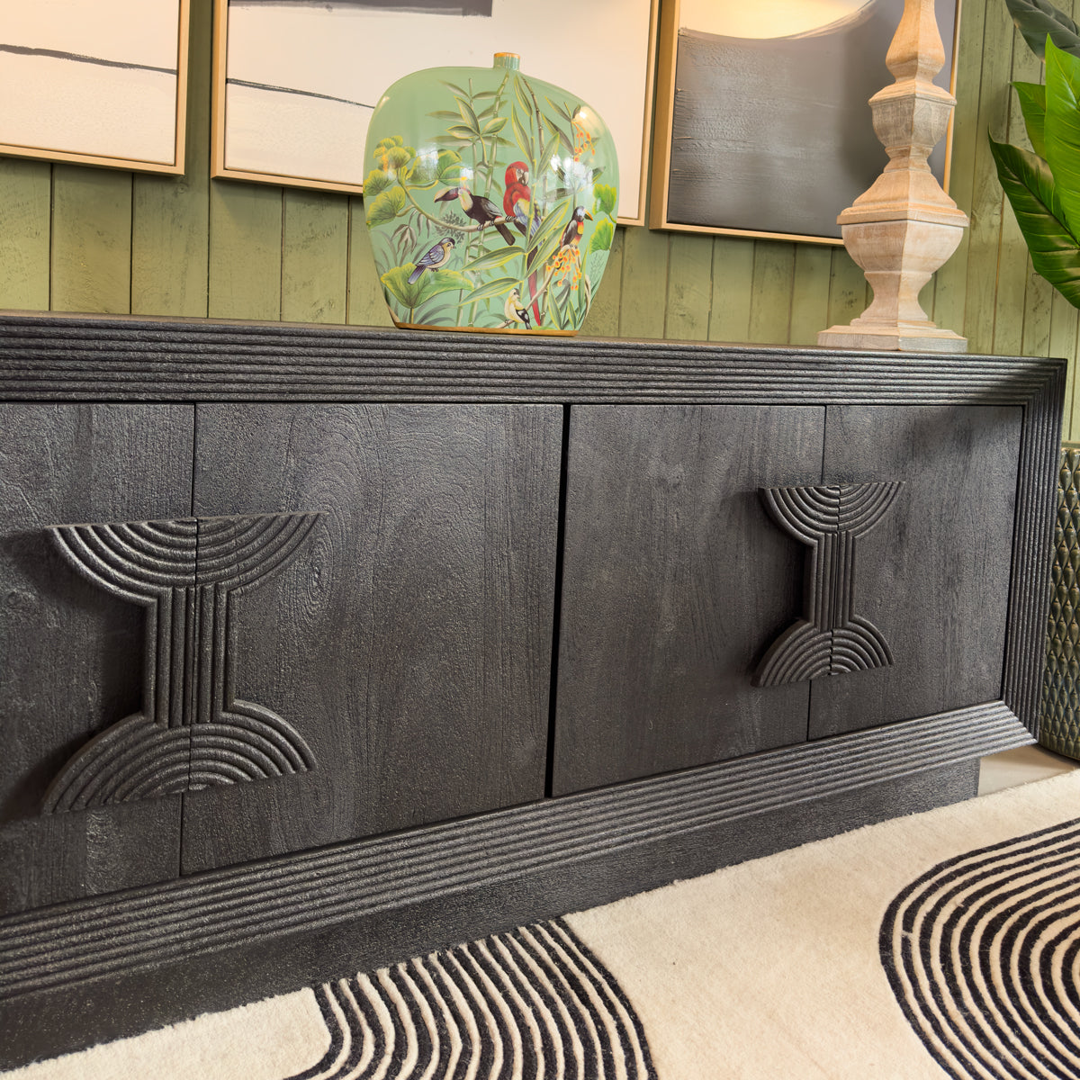 Dark wooden console table with decorative items against a green wall.