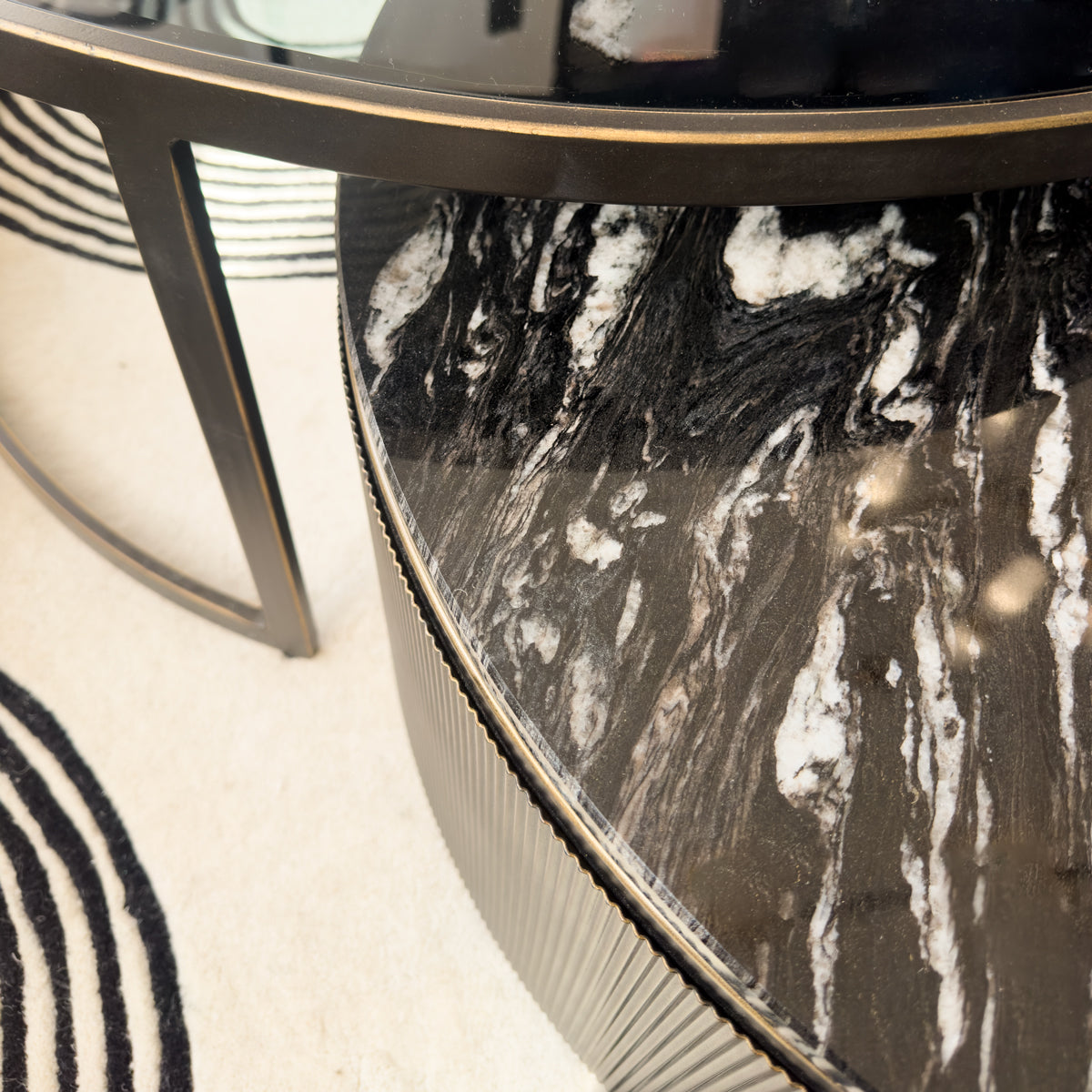 Round glass table with black and white marble top on a light-colored floor.