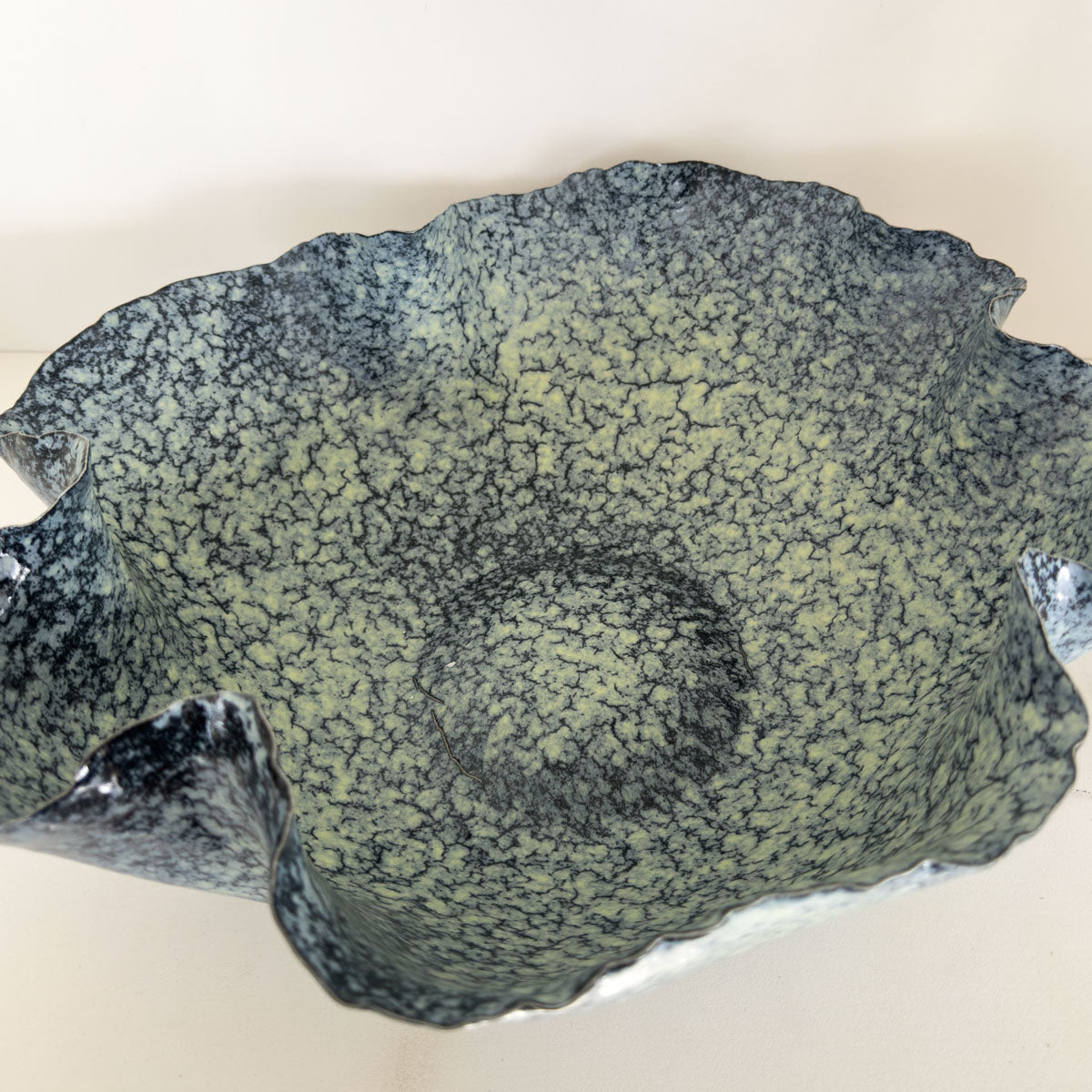 Decorative ceramic bowl with a textured  blue surface on a beige background