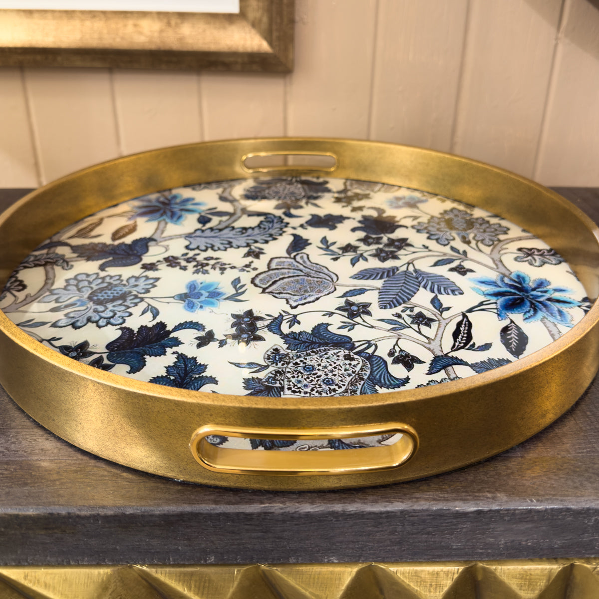 Round decorative tray with floral design and gold rim on a wooden surface
